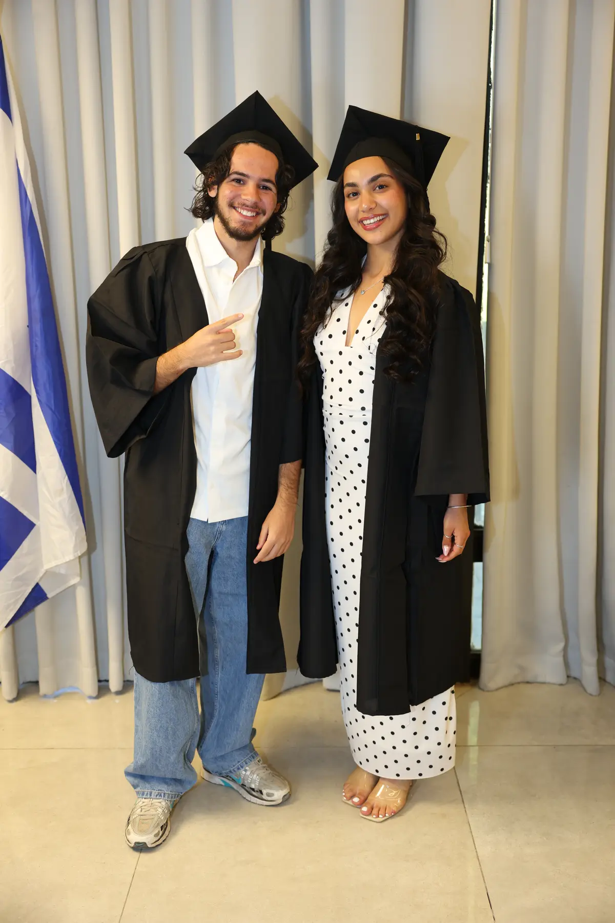זוג בוגרים בגלימות וכובעים תואמים